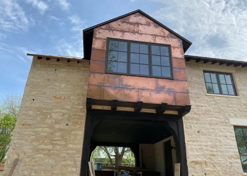 Copper metal panel facade on a stone building for Roof Repair in Houlton